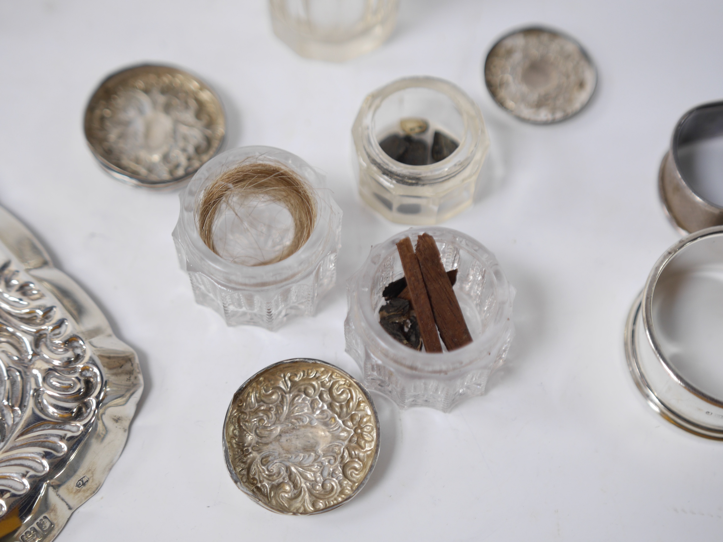 An Edwardian repousse silver dressing table tray by William Comyns, London, 1901, 23.3cm, together with four assorted silver mounted glass toilet jars, two silver mounted glass salts and three napkin rings. Condition - p